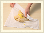 白こしあんとゆで卵の黄身を合わせ、濡らしたさらしを使って折りたたむようにして混ぜ合わせます。